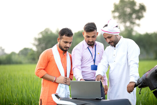 Sales man in Agri Field showing farmers the concept in laptop 