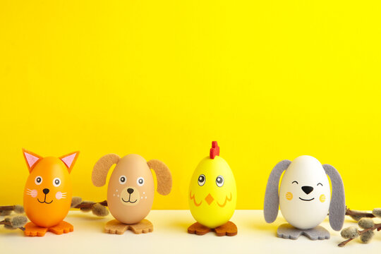 Easter holiday concept with cute handmade eggs, dogs, chicks and cat on yellow background.