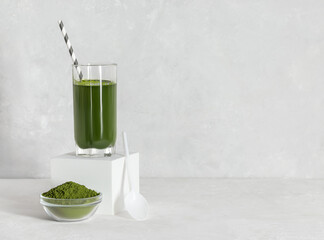 Chlorella detox drink in a glass and powder on a gray background. Superfood. Green drink with algae. Space for text.