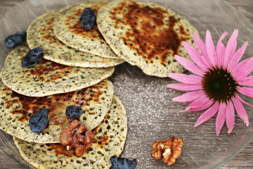 Pancakes with fresh raspberries, mint and jam on a black table with lonicera