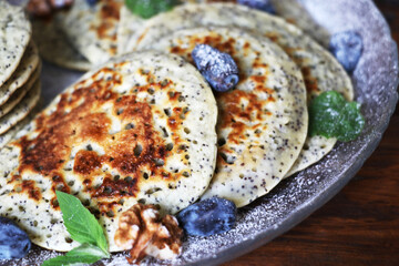 Pancakes with fresh raspberries, mint and jam on a black table with lonicera
