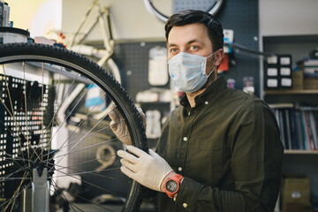 Bicycle shop repairman works in bicycle service and repair workshop during coronavirus quarantine...