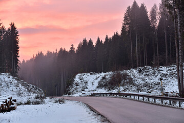 Naklejka premium Winter sunset over an empty forest road in the mountains