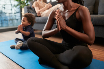 Mother and little son sitting on yoga mat and meditating in lotus position