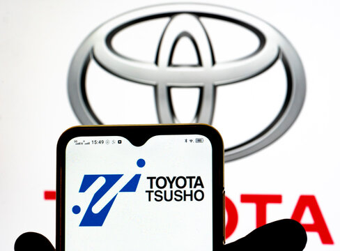 In this photo illustration, the Toyota Tsusho Corporation logo is seen displayed on a smartphone screen with the Toyota logo in the background.