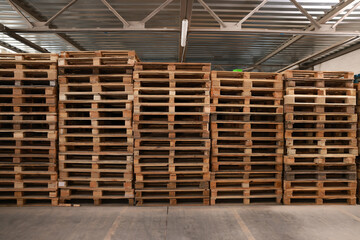 Many empty wooden pallets stacked in warehouse