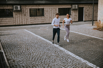 Young fitness couple running in urban area