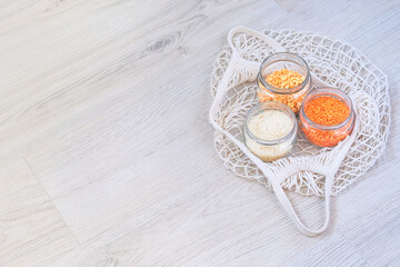 Grains and cereals in zero waste shop. Organic bulk products in kitchen. Lentils, peas and rice in glass jars on wooden background. Eco friendly shopping. Copy space.