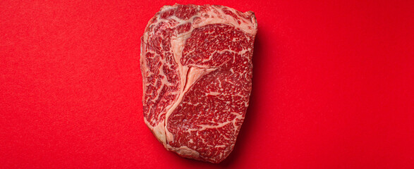 Raw meat beef prime cut steak Ribeye on clean red background from above, beefsteak concept banner minimalism with space for text