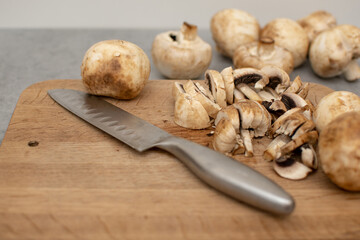 Raw delicious fresh white champignon on a wooden chopping board. Vegetarian recipe. Ingredients for cooking. Sliced portobello mushrooms on a light background.