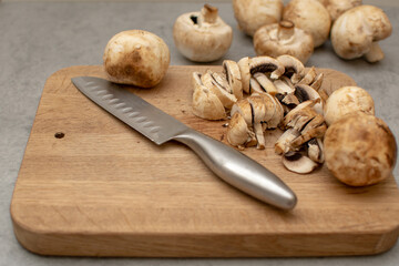 Raw delicious fresh white champignon on a wooden chopping board. Vegetarian recipe. Ingredients for cooking. Sliced portobello mushrooms on a light background.