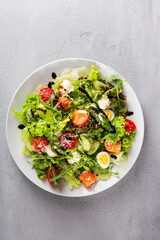 Top view of fresh salad with salmon slices and cheese on white plate