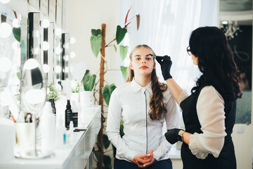 a girl in a beauty salon has an eyebrow lamination procedure, smears with white paste