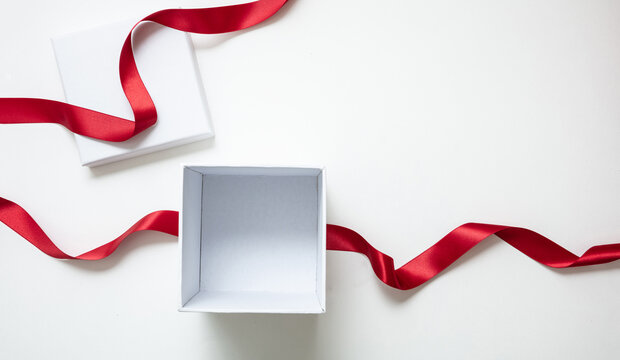 Valentine day gift, open white box and red satin ribbon isolated on white, empty space.