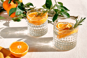 Summer refresh orange cocktail with ice, herb and ripe bio citrus fruits on linen tablecloth....