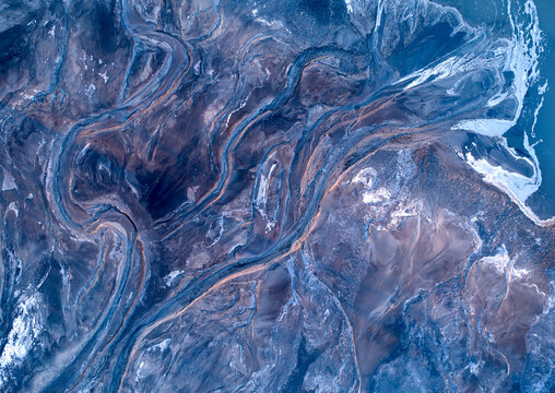 Aerial abstract landscape. Erosion created by water, blue shadows and pink-lit shapes. 