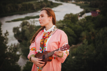 portrait young woman in ethnic dress lies with ukulele in hands