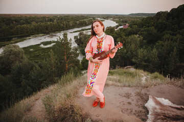portrait young woman in ethnic dress lies with ukulele in hands