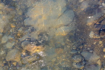 Obraz premium water flowing over rocks and ice in mountain river