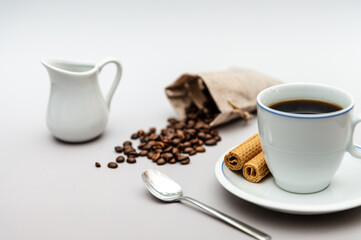 Coffee cup with biscuits, milk jug and coffee beans
