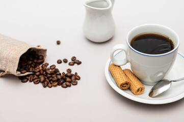 Coffee cup with biscuits, milk jug and coffee beans