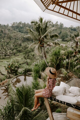 Young woman relaxing in a hotel in Bali, Indonesia, surrounded by jungle, palm trees and rice fields.