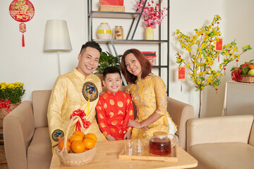 Happy parents and children sitting at table with mandarins and tea pot prepared for Chinese New...