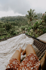 Young woman relaxing in a hotel in Bali, Indonesia, surrounded by jungle, palm trees and rice...