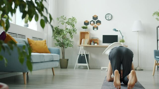 Slow motion portrait of experienced yoga student doing headstand training alone in apartment. Sports activities and healthy youth concept.