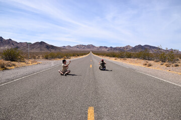 Fototapeta premium Two people pretending to drive on a highway in the Death Valley