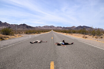 Two people pretending to lay dead on a highway in the Death Valley