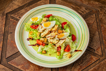 Caesar salad with grilled chicken breast, lettuce, cherry tomatos, boiled egg, croutons, seasoning
