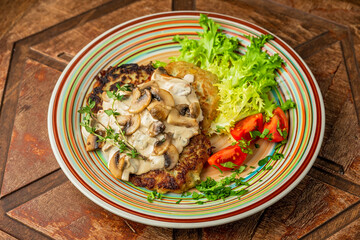 Potato pancakes with mushroom cream sauce, lettuce, cherry tomatos and thyme, wooden table