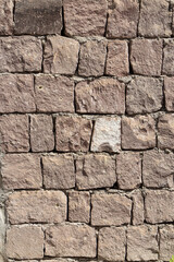 Fototapeta premium Beautiful texture of an old wall from orange stones with cracks. Vertical