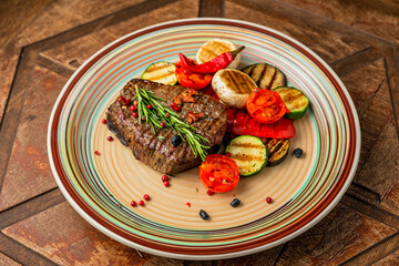 Beef steak with grilled vegetables garnish, zucchini, aubergine, mushroom, pepper, rosemary, cherry tomato
