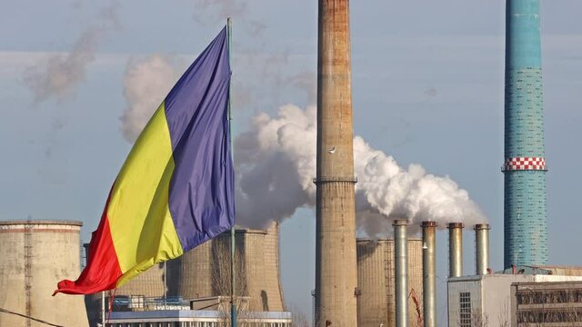 Romanian flag waving with CET Sud Bucharest Thermal Power Plant in the background. Cold winter day. Concept for pollution in Romania.