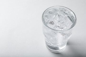 Glass of soda water with ice on light background. Space for text