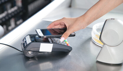 Fototapeta premium Customer paying for purchases contactless with smartphone.