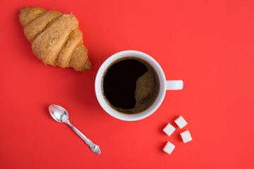 Top view of croissant and coffee cup on the red background. Copy space. Close-up.