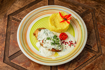 Baked chicken breast with cream sauce, served with rice for garnish and thyme