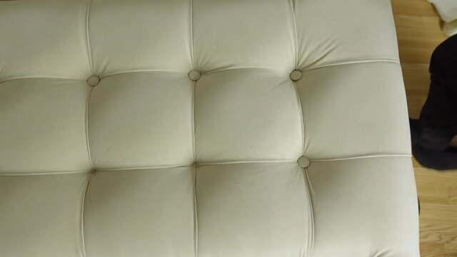 Man's hands upholster bed with new fabric and insert buttons with sewing needle