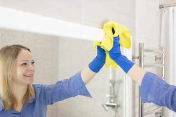 girl washes the mirror in the bathroom cleaning concept
