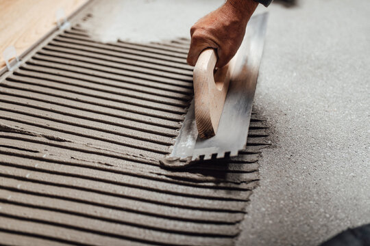 Flooring And Tiling. Professional Tiler Placing Floor Tiles On Adhesive Surface.