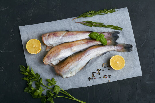 raw pollock fish lemon parsley rosemary flat lay top view black background copy space
