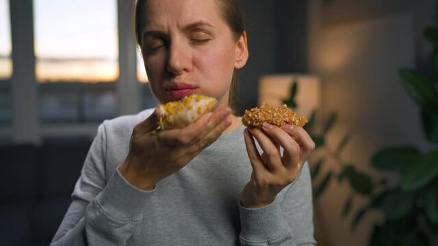 Binge eating concept. Caucasian woman with eating disorder eating two donuts quickly and at the same time.