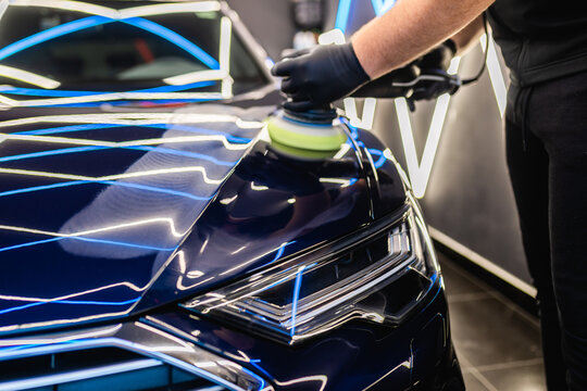 Car detailing - Man with orbital polisher in repair shop polishing car. Selective focus..