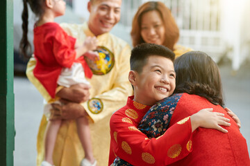 Excited smiling preteen boy hugging grandmother when his family visiting granparents for Tet celebration