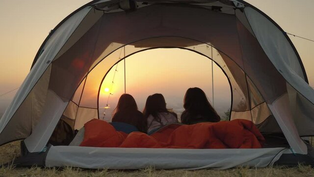 girl friend group Asians laying in tents during camping are waking up to watch the sun rise and shoot video from their action cams to show off to their friends in social media, the concept of adventur