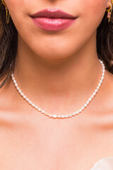 Beautiful young woman wearing a pearl necklace and golden earings.  Beautiful valentine's gift.