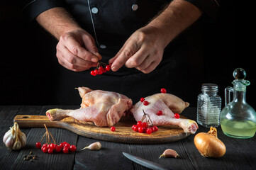 The chef prepares raw chicken legs in the restaurant kitchen. The cook puts the red viburnum on the chicken leg before baking. National dish
